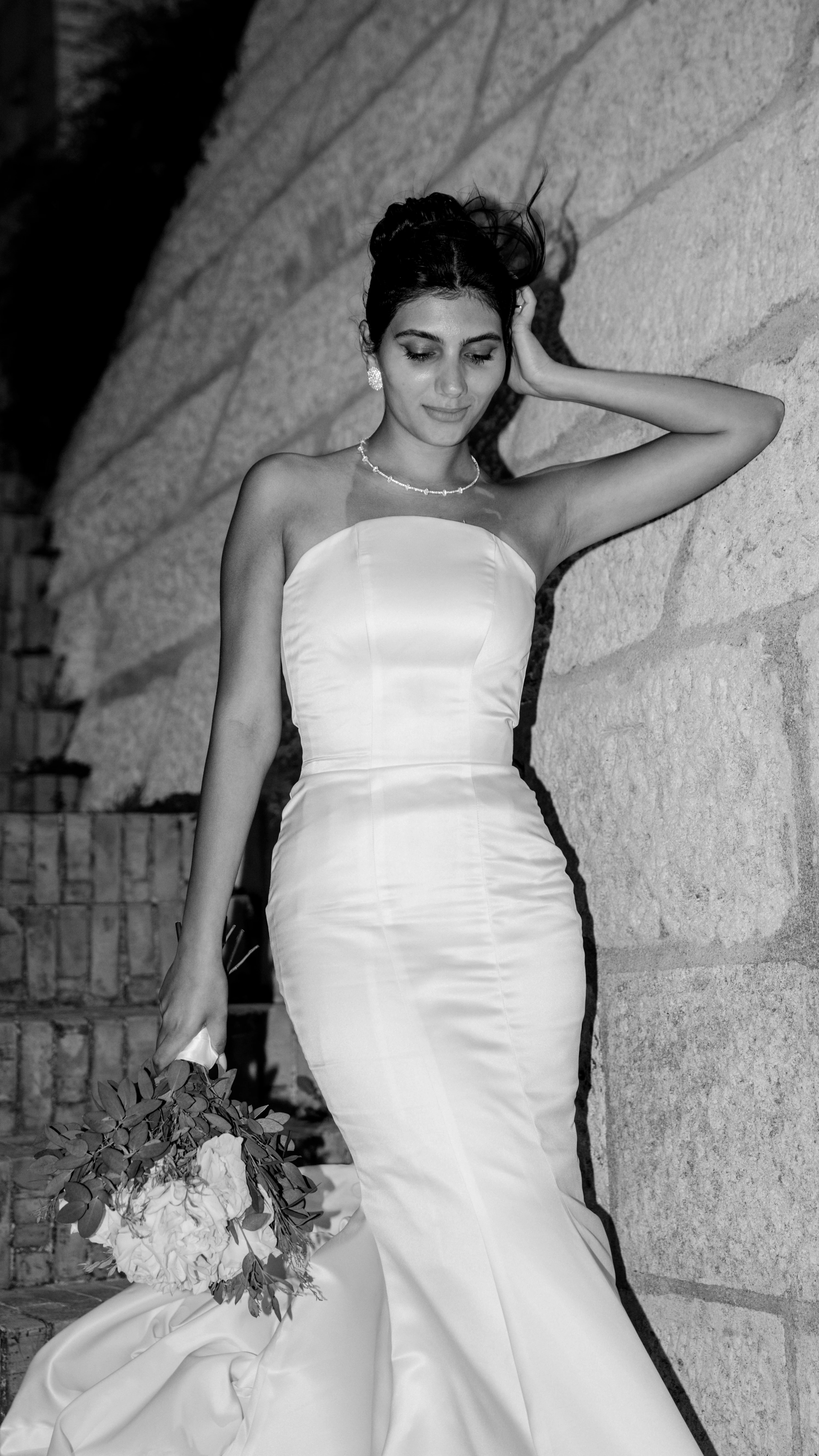 La sposa appoggiata a un muro di pietra, in bianco e nero