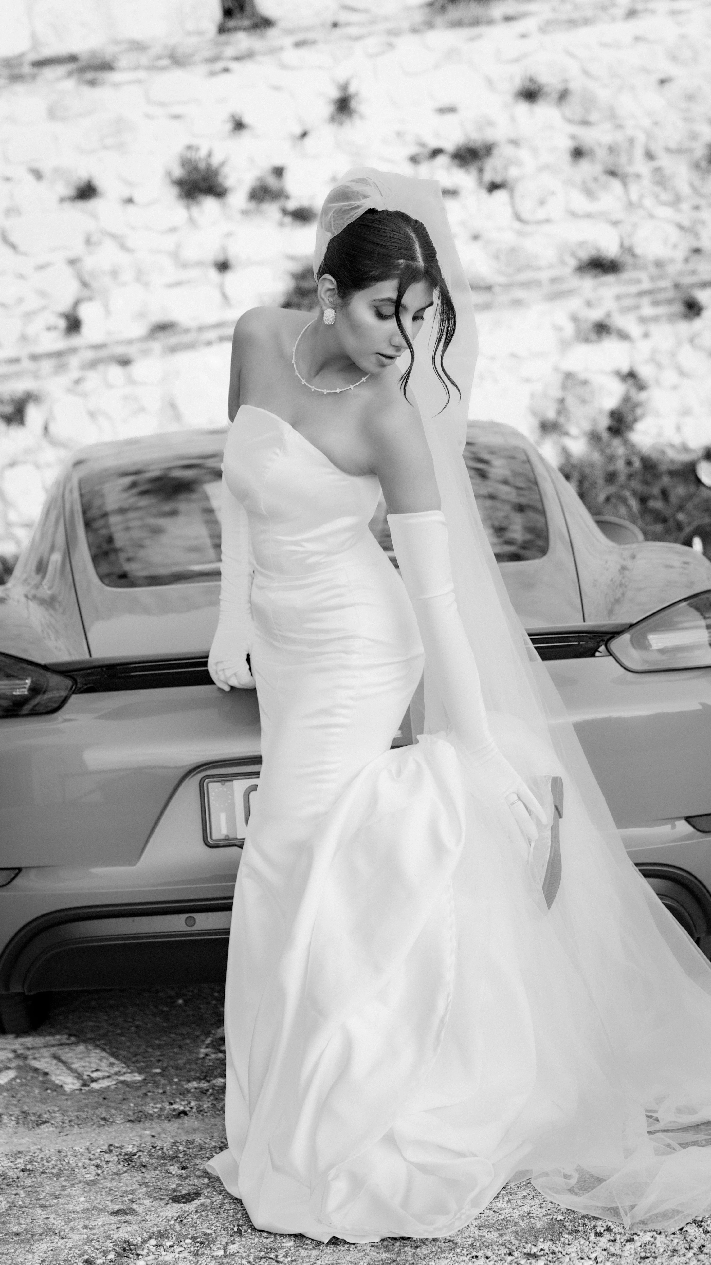 La sposa appoggiata all'auto, ritratto in bianco e nero